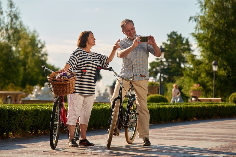 Retired couple taking photographs while on bicycles